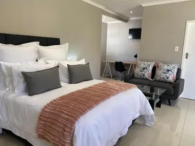a bedroom with a large bed and a chair at The Manor in Midrand