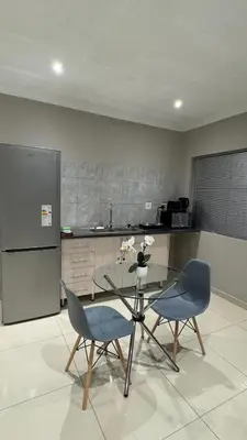 a kitchen with a table and two chairs and a refrigerator at The Manor in Midrand
