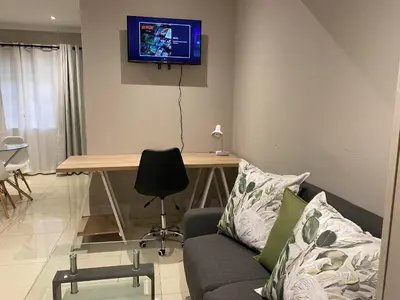 a living room with a couch and a table with a tv on the wall at The Manor in Midrand