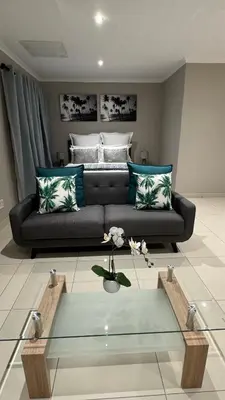 a living room with a couch and a glass coffee table at The Manor in Midrand