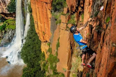 a man rock climbing on a cliff next to a waterfall at Climber's house in Waterval Boven