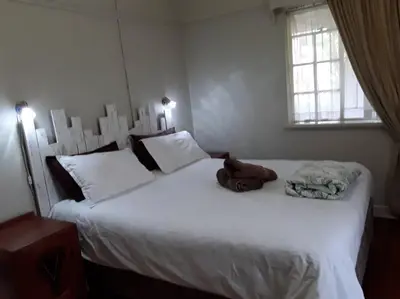 a bedroom with two beds with white sheets and a window at Climber's house in Waterval Boven