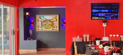 a room with a red wall with a picture on the wall at Tee Cee Marvelous Guesthouse in Thabazimbi
