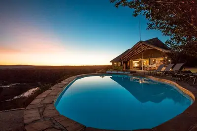 a large blue swimming pool in front of a house at Magari Safari Villa in Vaalwater