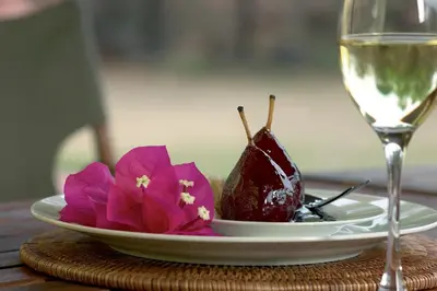 a plate of food with flowers and a glass of wine at Magari Safari Villa in Vaalwater