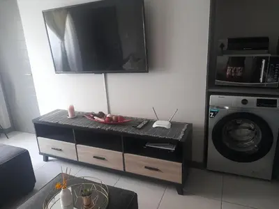 a living room with a tv and a washing machine at Neat Appartment, Fourways in Midrand