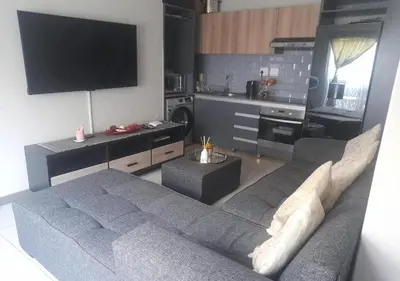a living room with a couch and a tv at Neat Appartment, Fourways in Midrand