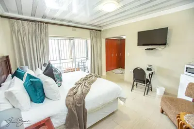 a bedroom with a large bed and a television at Zoe BnB in Midrand