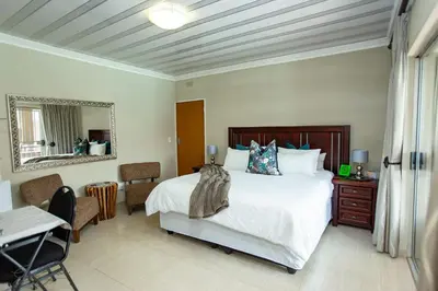 a bedroom with a bed and a table and a desk at Zoe BnB in Midrand
