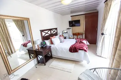 a bedroom with a large bed and a mirror at Zoe BnB in Midrand
