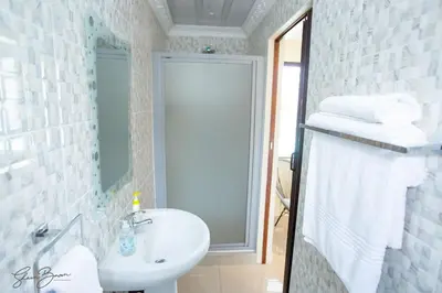 a bathroom with a sink and a shower with towels at Zoe BnB in Midrand