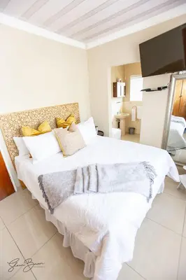 a white bedroom with a large white bed with yellow pillows at Zoe BnB in Midrand