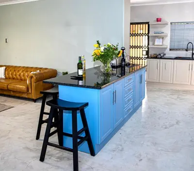 a kitchen with a blue island with a black counter top at Origon Farmhouse in Brits