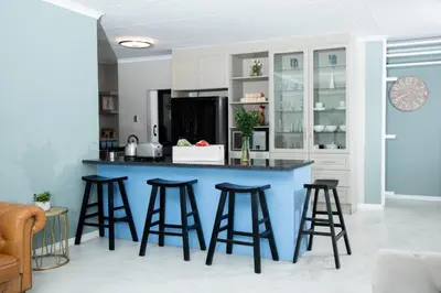 a kitchen with a blue island with bar stools at Origon Farmhouse in Brits