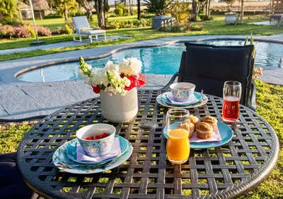 a table with food and drinks on it next to a pool at Origon Farmhouse in Brits