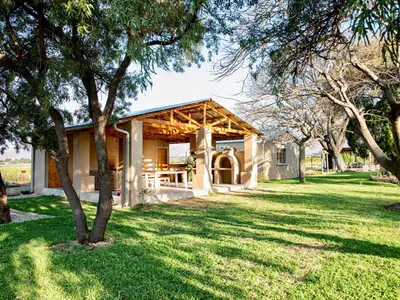 a house in a field with trees in front of it at Origon Farmhouse in Brits