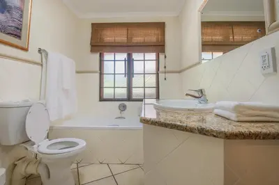 a white bathroom with a toilet and a sink at Kruger Park Lodge Unit No. 241 in Hazyview