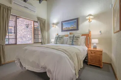 a bedroom with a large white bed and two windows at Kruger Park Lodge Unit No. 241 in Hazyview