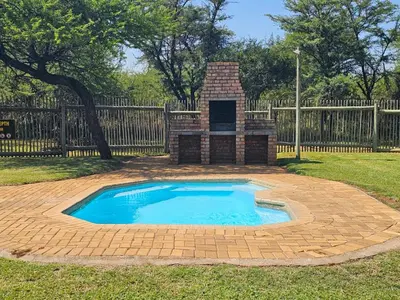 a small pool with a brick fireplace in a yard at Makhato Bush Lodge 48 in Bela-Bela