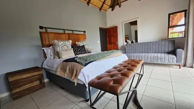 a bedroom with a bed and a chair and a couch at Makhato Bush Lodge 48 in Bela-Bela