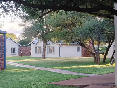 a house with trees and a sidewalk in the grass at Mukumbura Swartwater in Swartwater