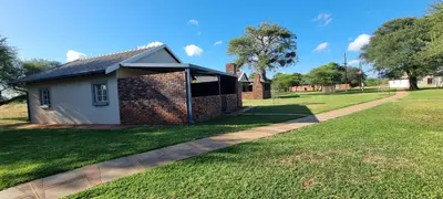 a small white house with a brick wall at Mukumbura Swartwater in Swartwater