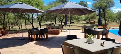 a restaurant with tables and umbrellas on a patio at Mukumbura Swartwater in Swartwater