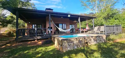 a house with a porch with a swing and a pool at Robin Cottage Da Gama Lake in White River