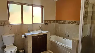 a bathroom with a toilet and a sink and a tub at Robin Cottage Da Gama Lake in White River