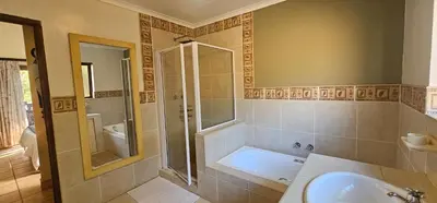 a bathroom with a shower and a tub and a sink at Robin Cottage Da Gama Lake in White River