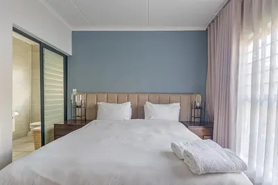a bedroom with a large white bed and a window at Modern 3-bed Garden Apartment in Waterfall in Midrand