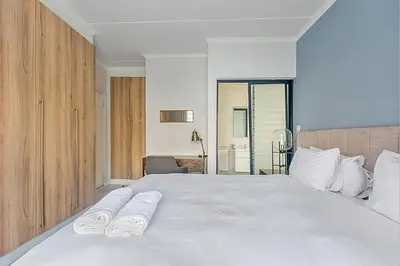 a bedroom with a large white bed with towels on it at Modern 3-bed Garden Apartment in Waterfall in Midrand