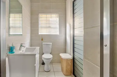 a white bathroom with a toilet and a sink at Modern 3-bed Garden Apartment in Waterfall in Midrand