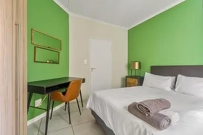 a bedroom with a bed with a desk and a bed sidx sidx sidx at Modern 3-bed Garden Apartment in Waterfall in Midrand