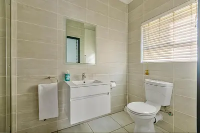 a bathroom with a toilet and a sink and a mirror at Modern 3-bed Garden Apartment in Waterfall in Midrand