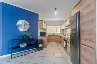 a kitchen with a blue wall and a mirror at Modern 3-bed Garden Apartment in Waterfall in Midrand