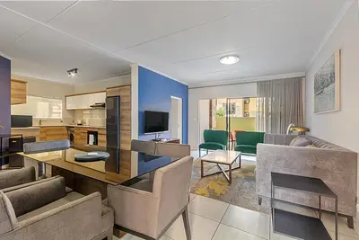 a living room with a couch and a dining room at Modern 3-bed Garden Apartment in Waterfall in Midrand
