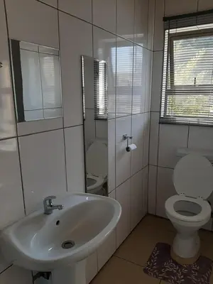 a white bathroom with a toilet and a sink at Fumas guesthouse in Duvhapark