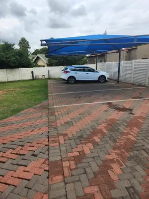 a white car parked under a blue canopy in a driveway at Fumas guesthouse in Duvhapark