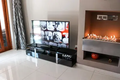 a living room with a flat screen tv and a fireplace at Modern Home in Pretoria near Menlyn Mall in Pretoria