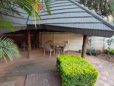 a patio with a table and chairs under a roof at B&O's Place in Pretoria