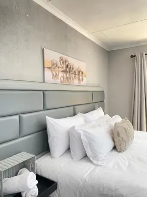 a bed with white pillows and a painting on the wall at THABAKGOLO GUEST HOUSE in Ga-Manapane