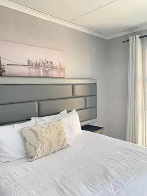 a bedroom with a white bed with a blue headboard at THABAKGOLO GUEST HOUSE in Ga-Manapane