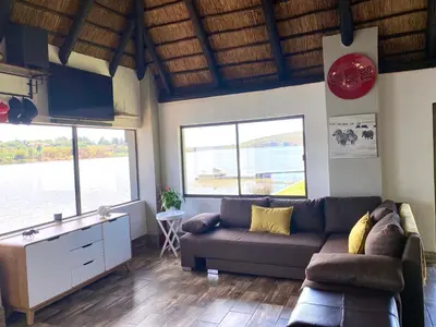 a living room with a couch and two windows at LAKE-HOUSE CABIN in Witbank