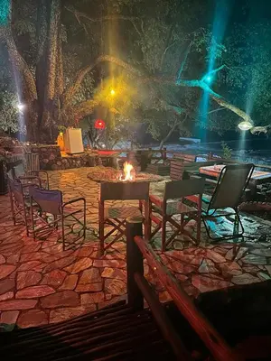 a group of chairs and a table with a fire at JakkalsDraai River Bush Lodge in Hoedspruit