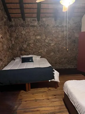 a bedroom with a bed and a stone wall at JakkalsDraai River Bush Lodge in Hoedspruit
