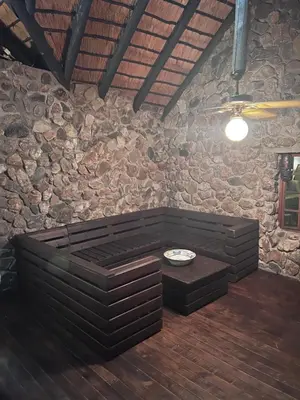 a room with a stone wall with a table and benches at JakkalsDraai River Bush Lodge in Hoedspruit