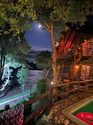 a resort with a pool and a tree house at night at JakkalsDraai River Bush Lodge in Hoedspruit