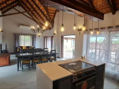 an open kitchen and dining room with a dining table at Hoedspruit Bush Stay in Hoedspruit