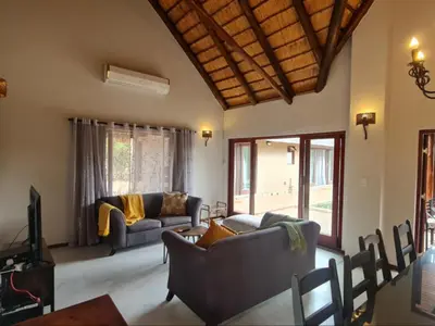 a living room with two couches and a tv at Hoedspruit Bush Stay in Hoedspruit